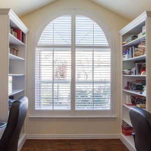 White shutters covering windows between bookshelves in home office