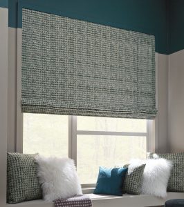 decorative Roman shades covering a window over a cozy sitting nook with pillows