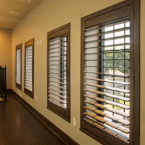wood plantation shutters covering a series of windows in a room with a wood floor