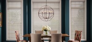 white colored wood blinds covering three windows inside a blue-toned dining room